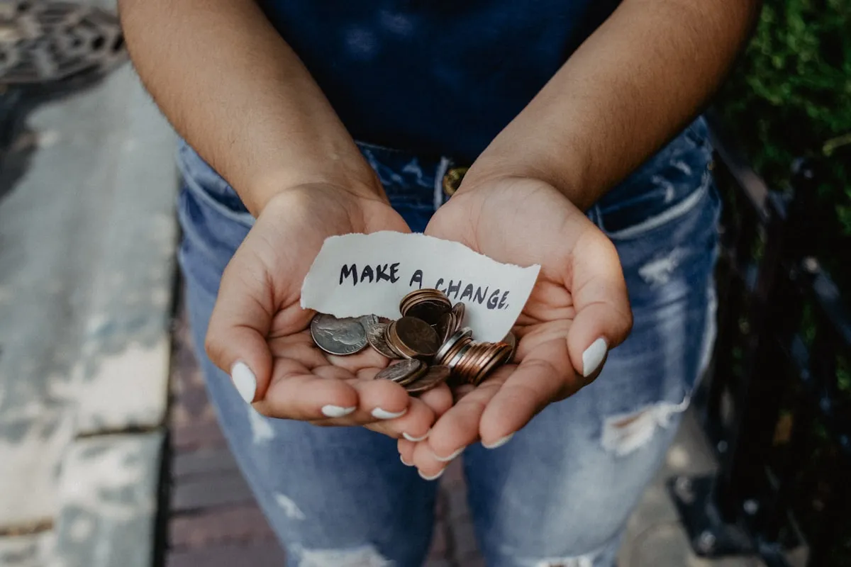 Cupped hands holding coins and a handwritten note reading 'make a change'